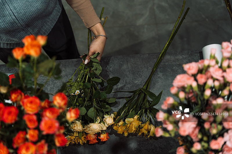 花艺师在深色柜台上整理花茎图片素材