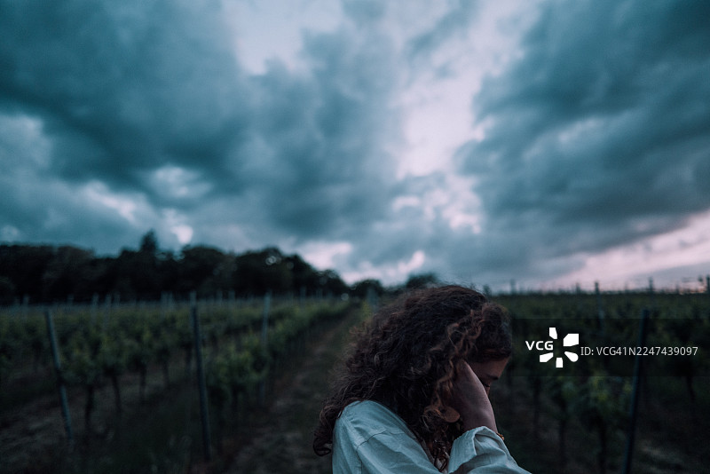 阴雨天下的葡萄园里，一位年轻女子带着沉思而忧郁的情绪图片素材