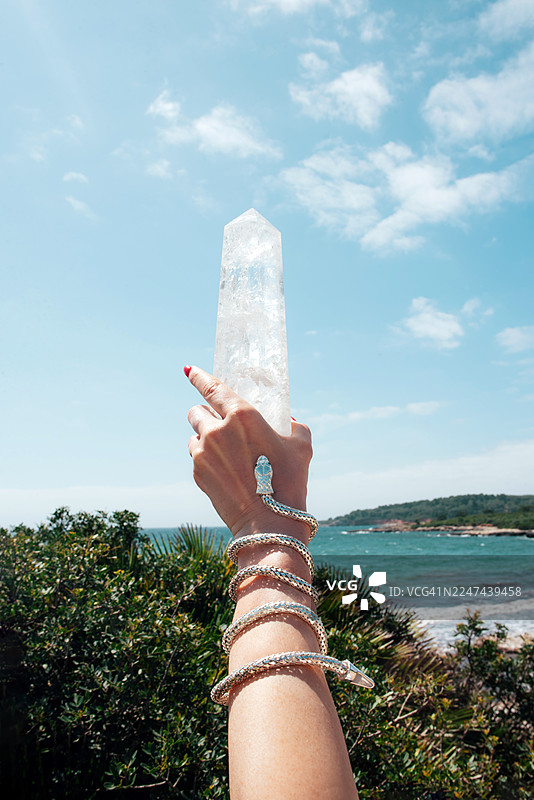 海边的大块水晶。紫水晶。萤石。硒。女人手里拿着一条银色蛇形手链的水晶。图片素材