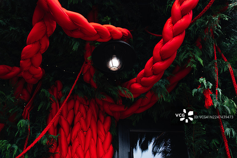 这座玻璃建筑的门面和商店入口处装饰着圣诞装饰品和圣诞树，房屋入口也被新年装饰点缀。图片素材