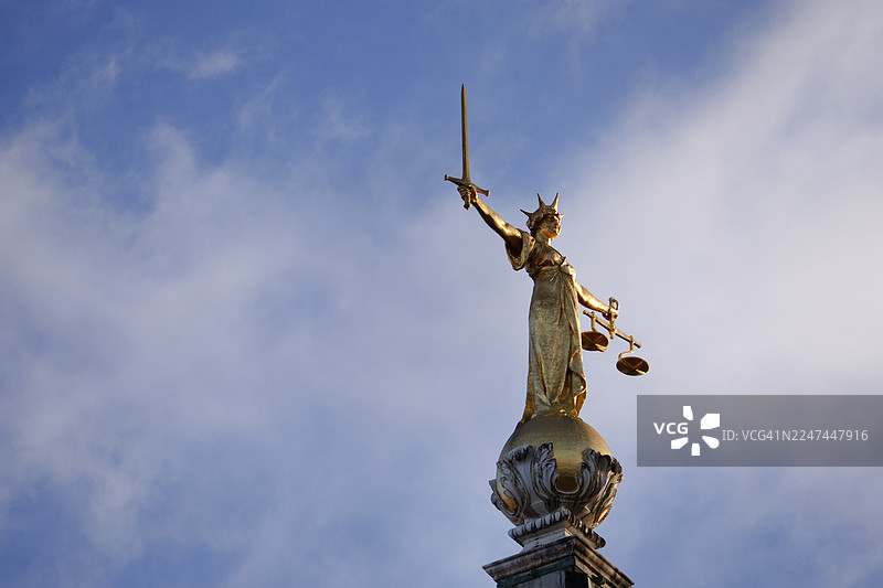 秋日晴朗，老贝利法院顶端正义女神雕像的特写图片素材