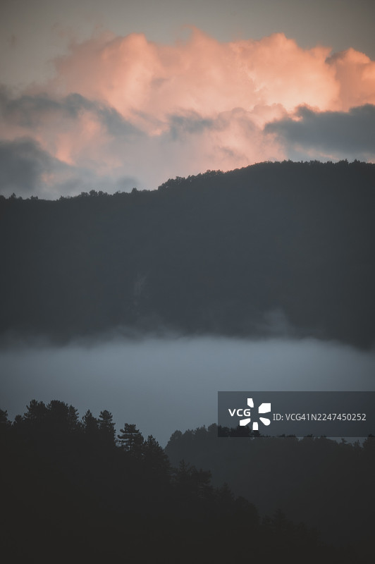 金色云层下的薄雾山谷，壮丽的日落景象图片素材