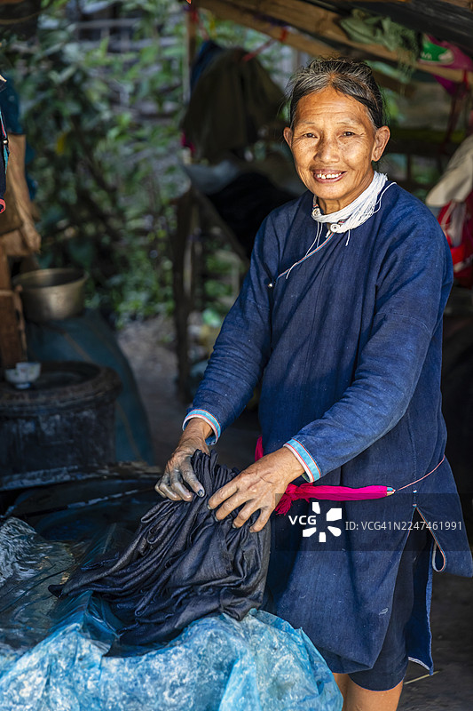 老挝北部村庄里，一位老挝妇女正在检查刚染好的布料图片素材