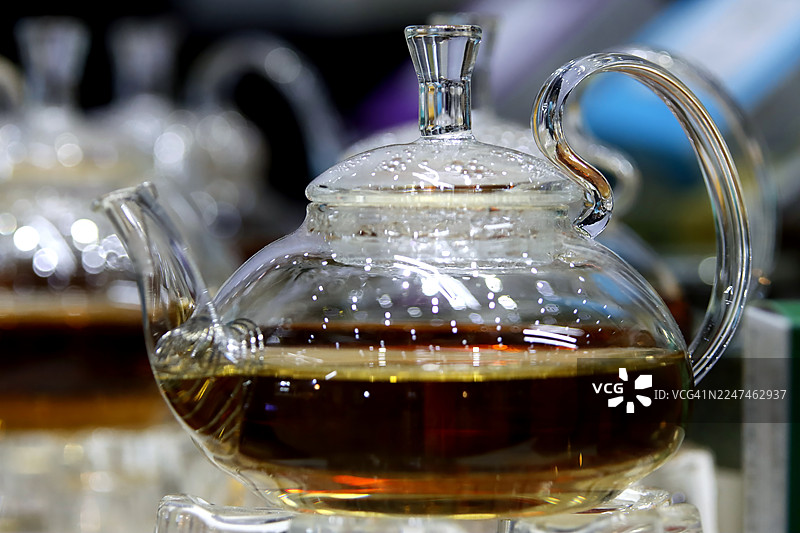 现代硼硅酸盐玻璃茶壶特写，壶内盛有深琥珀色冲泡好的茶图片素材