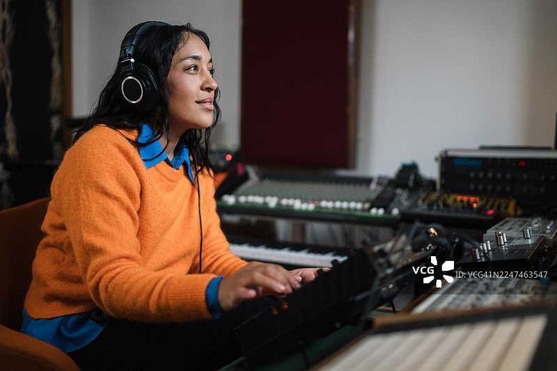 女士在专业的录音棚里用合成器制作音乐图片素材