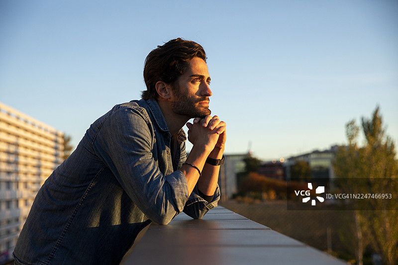 一位英俊的年轻男子在日落时分的街道上沉思，凝视远方图片素材
