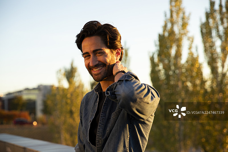 夕阳下，一位英俊的年轻男子在街上沉思，目光望向远方图片素材
