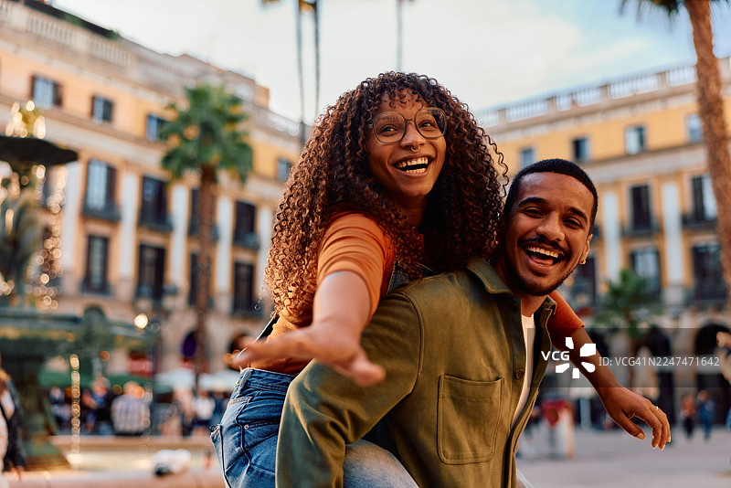 快乐的年轻情侣在巴塞罗那城市广场上玩背背游戏图片素材