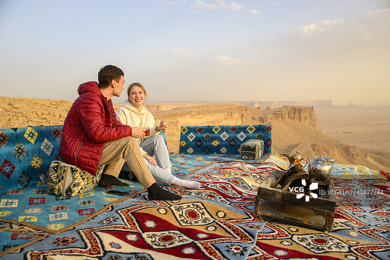年轻的游客情侣在利雅得附近图瓦伊克山脉世界之巅悬崖徒步后享用茶点图片素材