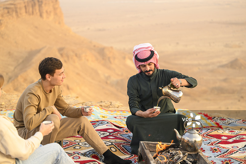沙特向“世界边缘”的徒步旅行者倒咖啡的向导图片素材