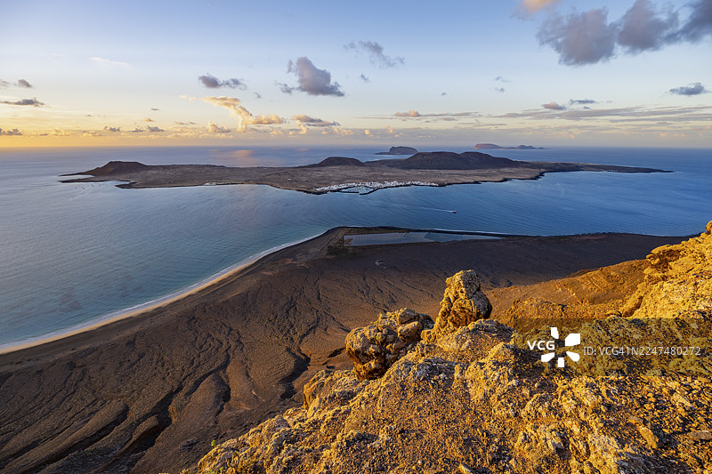 夕阳时分,从米拉多尔德尔波里托(Mirador del Porrito)观景点看到的兰萨罗特岛(Lanzarote)和加那利群岛(Canary Islands)的壮丽景色,包括陡峭的悬崖、大海以及拉格拉西奥萨岛(La Graciosa)。图片素材