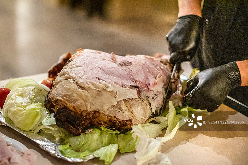 烤猪腿。猪腿。烤肉。厨师手工切割牛排。活动餐饮。图片素材