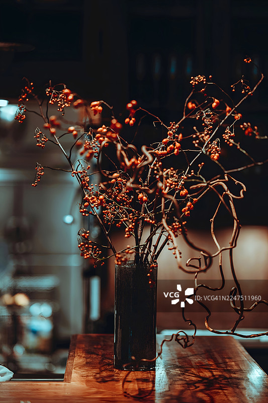 花瓶里装饰性的浆果和树枝特写，摆放在木桌上，营造出温馨宜人的氛围图片素材
