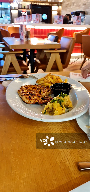 餐厅木桌上美味的烤鸡配薯条和土豆泥图片素材