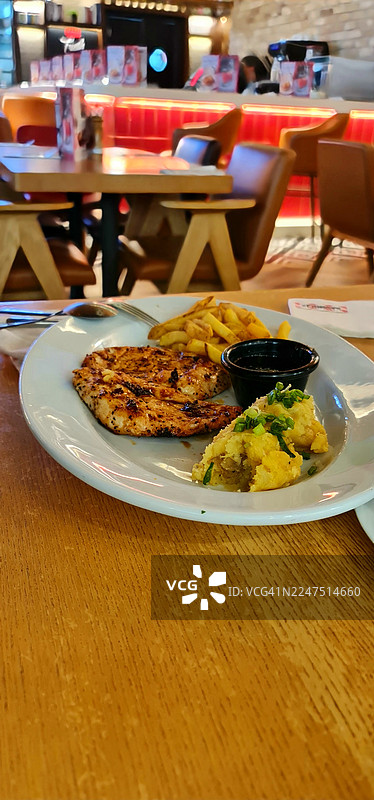 餐厅里，盘中盛放着美味的烤鸡、炸薯条和土豆泥。图片素材