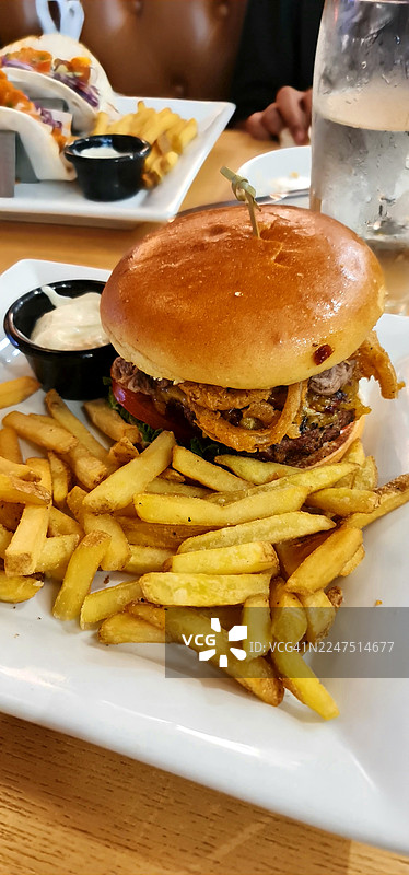 美味的汉堡配酥脆薯条和蘸酱，装在白盘上，即刻享用图片素材