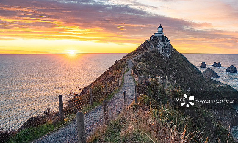 新西兰Ahuriri Flat的努盖特角灯塔，在日出时分，一座灯塔矗立在崎岖的悬崖上，海岸景色令人惊叹，海天一色，景色壮丽。图片素材