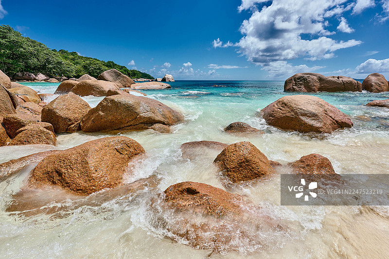 塞舌尔热带海滩上，蓝天下，碧绿海水与花岗岩巨石构成的风景图片素材