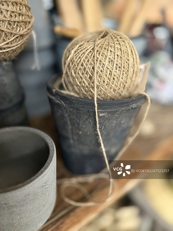 质朴的陶罐里装着一团天然麻绳，背景中还有另一个陶罐和麻绳，营造出温馨而有机的氛围图片素材