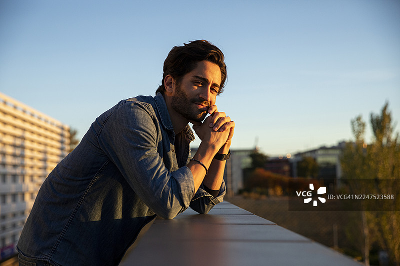 夕阳下，一位英俊的年轻男子在街上若有所思地凝视远方图片素材