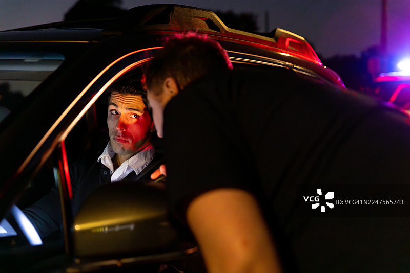 司机侧目看向身体前倾检查车内情况的警官图片素材
