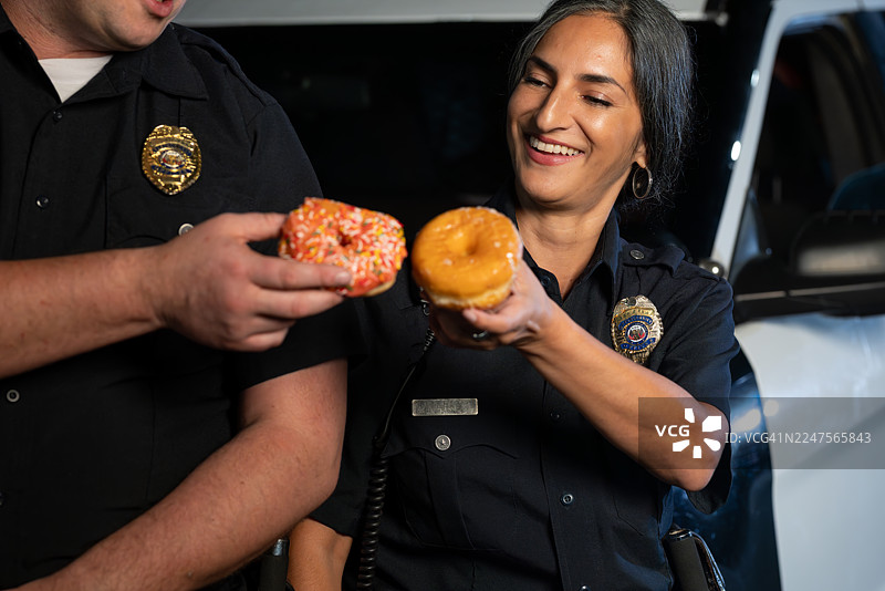 玩闹的下班警察们用甜甜圈庆祝碰杯图片素材