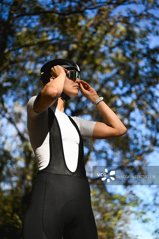 一名女骑行者在户外调整骑行太阳镜图片素材