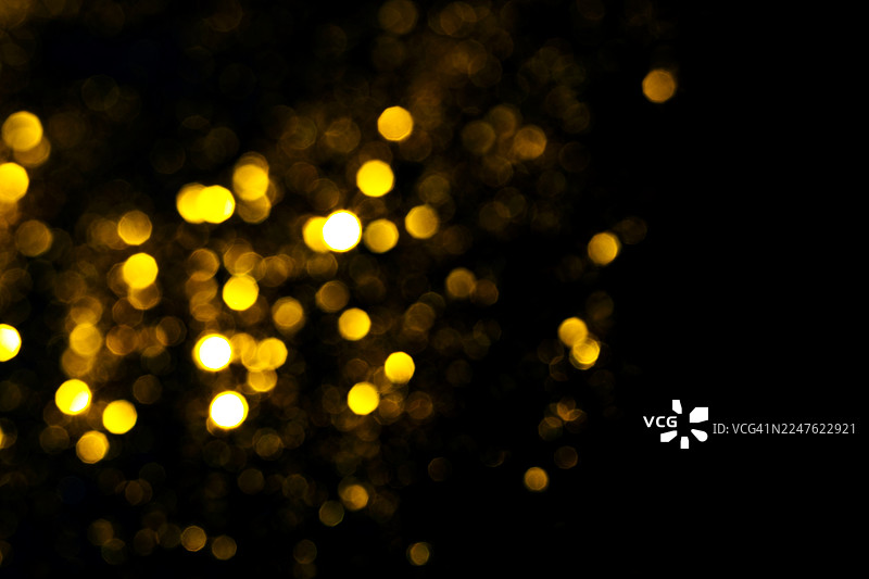 黑色背景上的金色散景灯光。闪烁的星星叠加图片素材