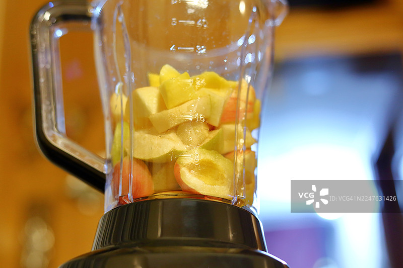 将切好的苹果、杏子和梨放入搅拌机，准备制作健康的冰沙。图片素材