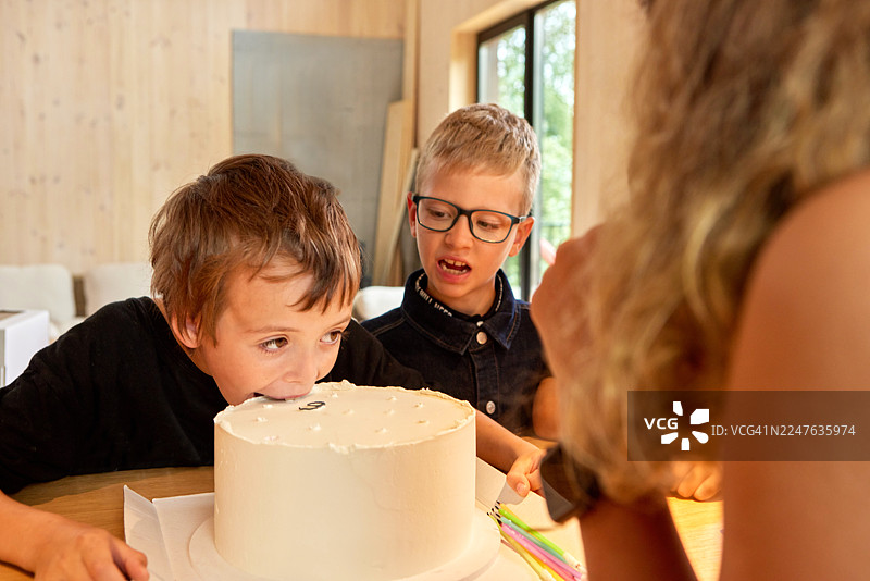 派对上男孩直接从盘子里吃生日蛋糕图片素材