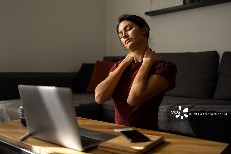 在家工作的女性因颈部疼痛而进行按摩图片素材