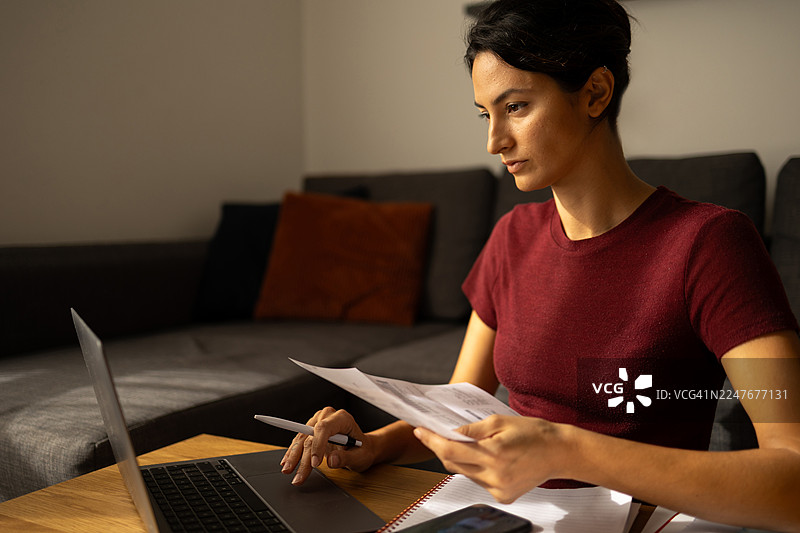 年轻女子在家中管理财务并工作图片素材