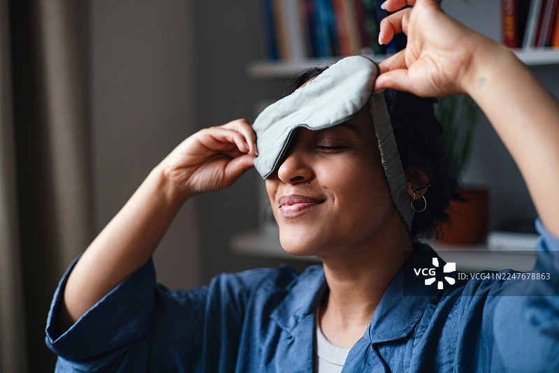 一位放松的女性在家中，在舒适的早晨例行活动中戴着睡眠眼罩图片素材