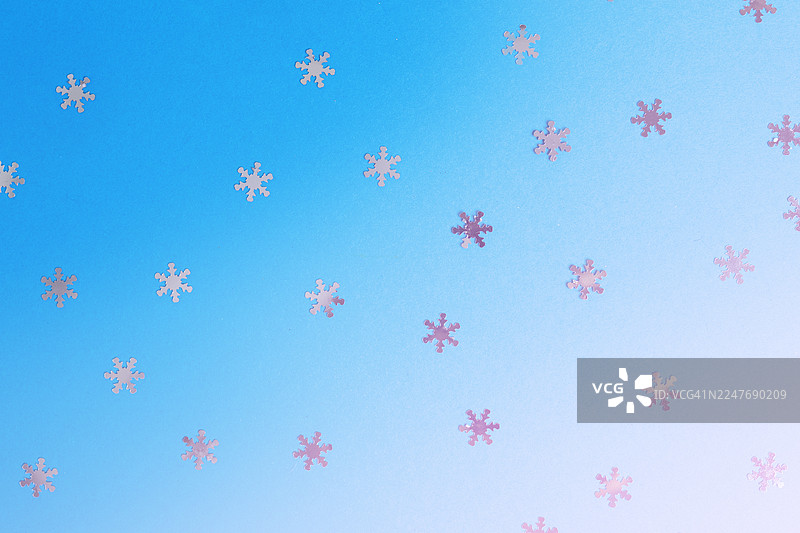 蓝色渐变背景上的飘落的银色雪花图片素材