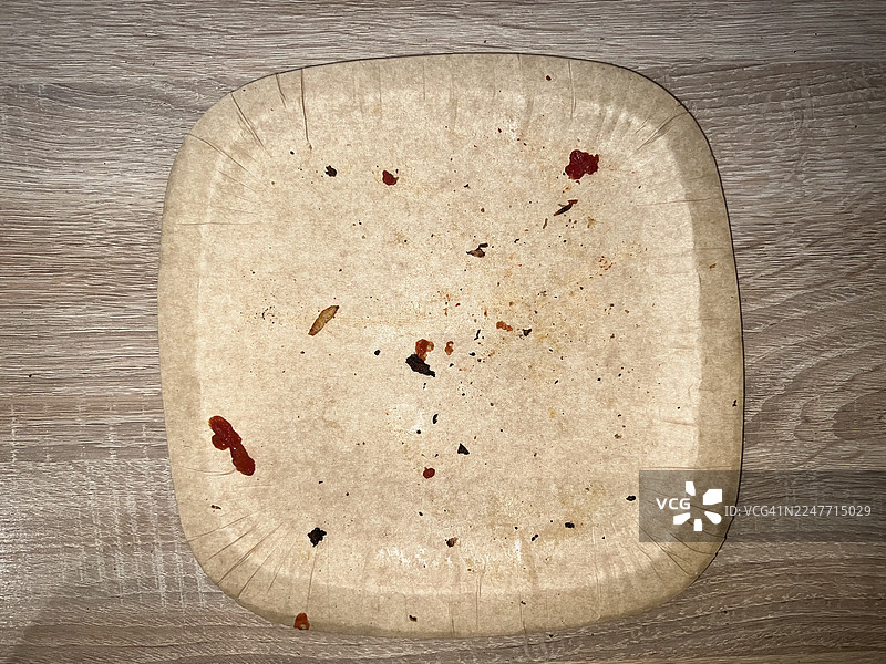 木制桌面上的空用过的纸盘，上面有披萨碎屑图片素材