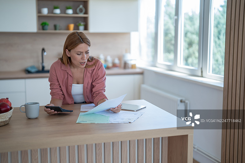 压力山大的女性在厨房里管理家庭账单和财务图片素材