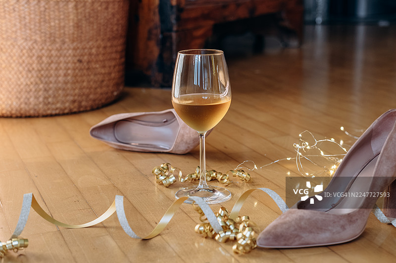 派对后的氛围背景，生日、婚礼、圣诞节、新年，黑色高跟鞋，周围环绕着节日装饰品和一杯酒，庆祝氛围图片素材