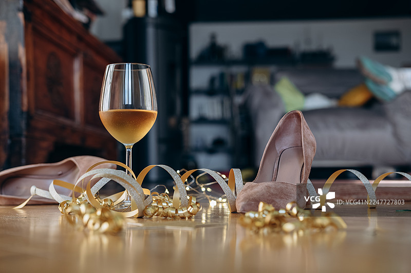 派对后的节日氛围背景，生日、婚礼、圣诞节、新年，黑色高跟鞋，周围环绕着节日装饰和一杯葡萄酒，庆祝气氛图片素材