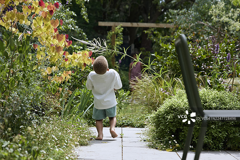 学龄前男童弯腰走在叶子下面图片素材