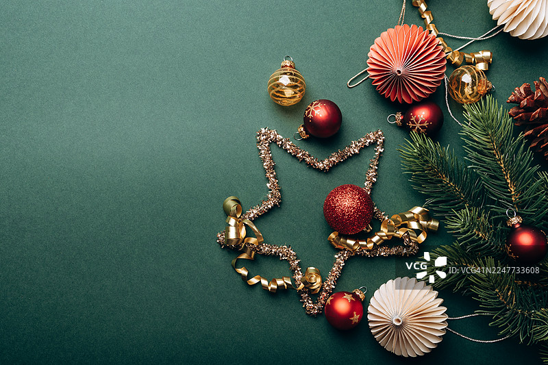 圣诞节日装饰背景，绿色背景上有一颗星星，装饰有饰品、彩带和松枝，用于季节性庆祝图片素材