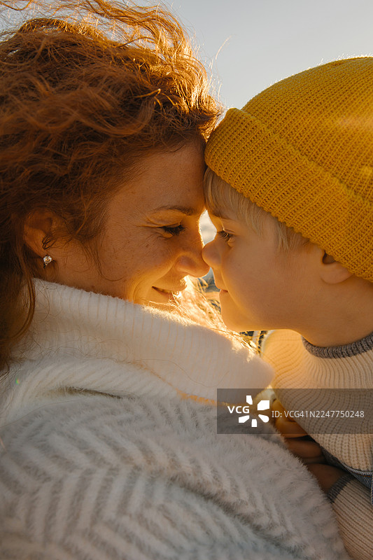 夕阳余晖中，母亲与孩子深情拥吻，温馨的家庭时光，充满喜悦。图片素材
