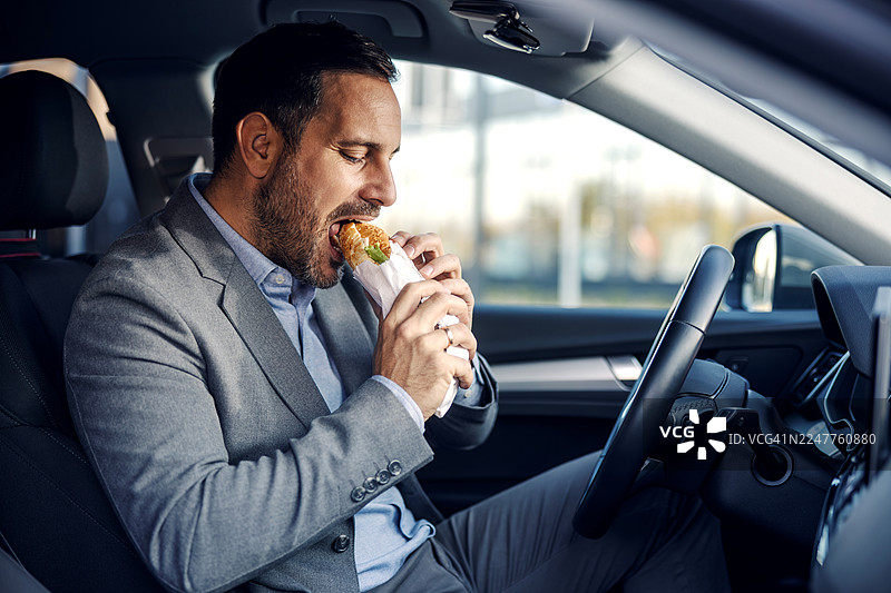 商务男士在拥挤的通勤时间里，在车里吃三明治图片素材