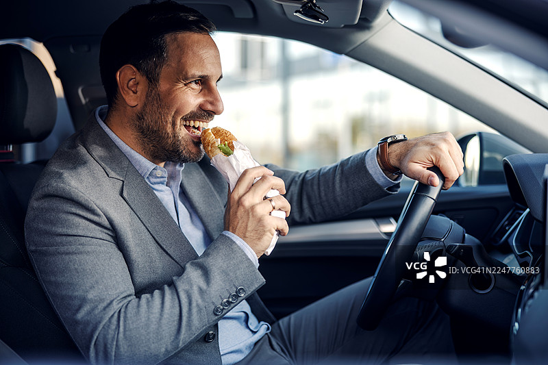 商务人士在开车时吃三明治图片素材