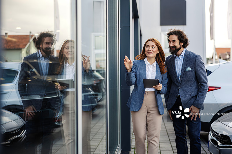 汽车经销商展厅销售人员协助顾客图片素材