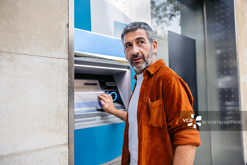 一名中年男子在西班牙巴塞罗那的自动取款机上取钱图片素材