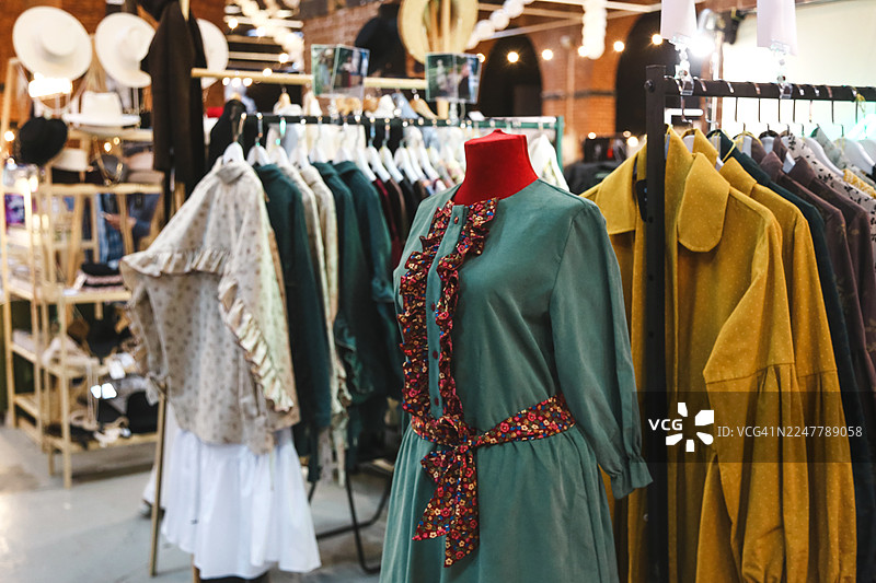 绿色褶皱棉质连衣裙，背景为模糊的服装店图片素材