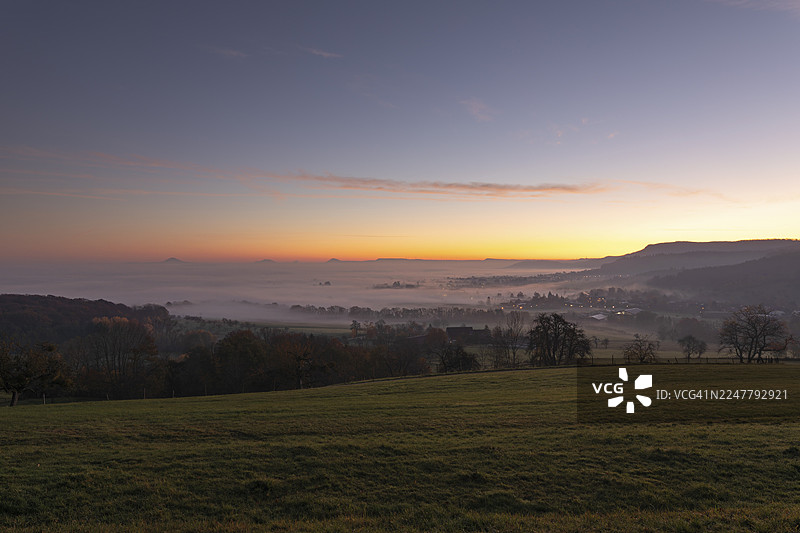 金色晨光中的三座凯泽山，霍恩施陶芬山、艾歇尔贝格山，巴登-符腾堡州雾气缭绕的丘陵上壮丽的黎明。德国巴登-符腾堡州菲辛根县的巴特博尔、艾克瓦尔登、杜恩瑙。图片素材