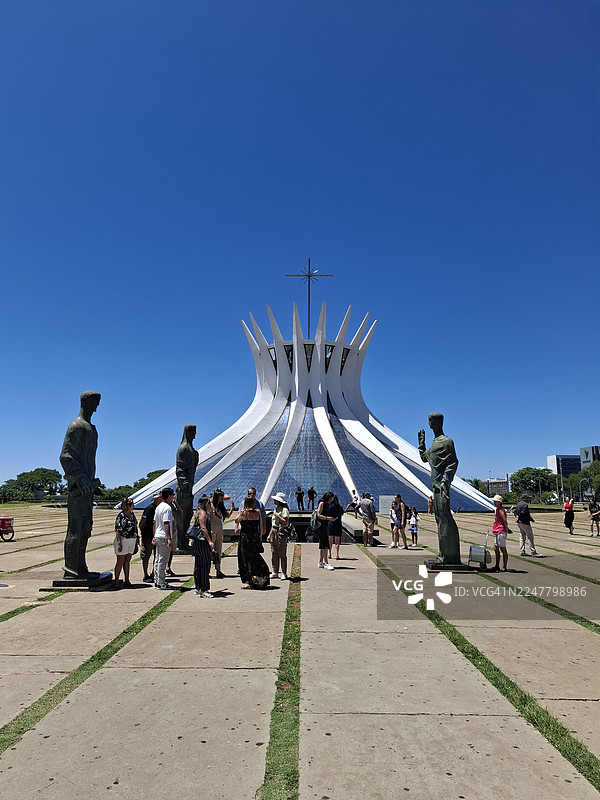 巴西利亚大都会大教堂（也称为巴西利亚大教堂）主入口处，四福音传教士（马太、马可、路加和约翰）铜像旁边的游客景象图片素材