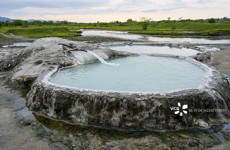 佐治亚州伊梅列季地区瓦尼的迪卡什霍硫磺间歇泉阿玛格莱巴温泉的天然温泉池，有广阔的草地和多云的天空，瓦尼，里奥尼河图片素材