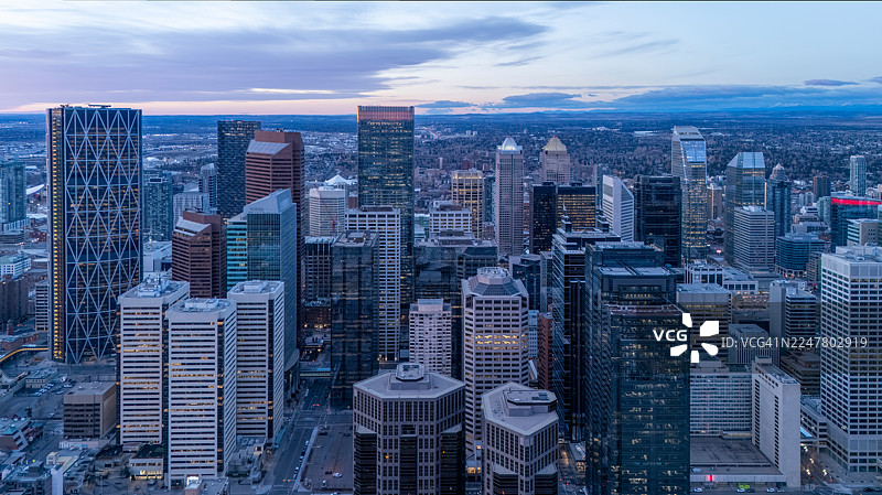 日出时卡尔加里市中心的广角航拍图——摩天大楼与远处的落基山脉图片素材